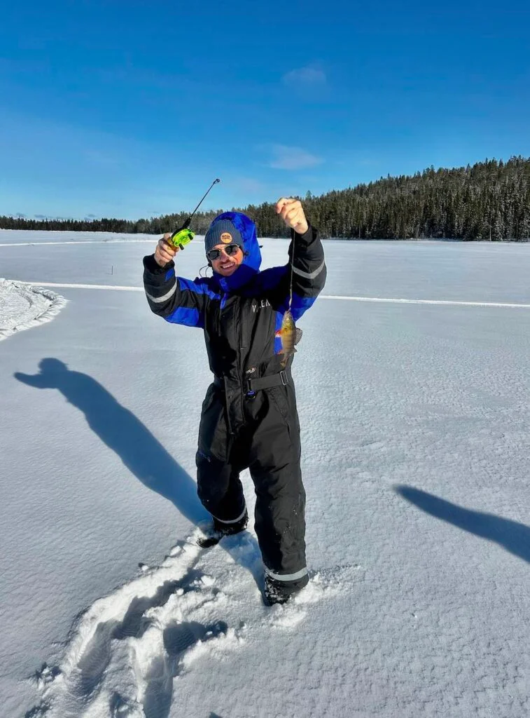 Pêcheur tenant sa prise sur un lac gelé en Laponie finlandaise