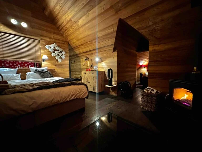 Chambre en bois d’un lodge AquaLodge avec lit double et poêle