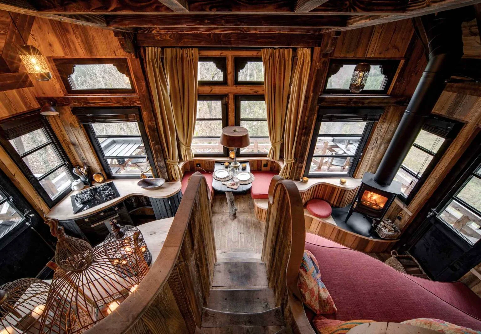 Intérieur chaleureux d’une cabane en bois avec poêle et fenêtres panoramiques