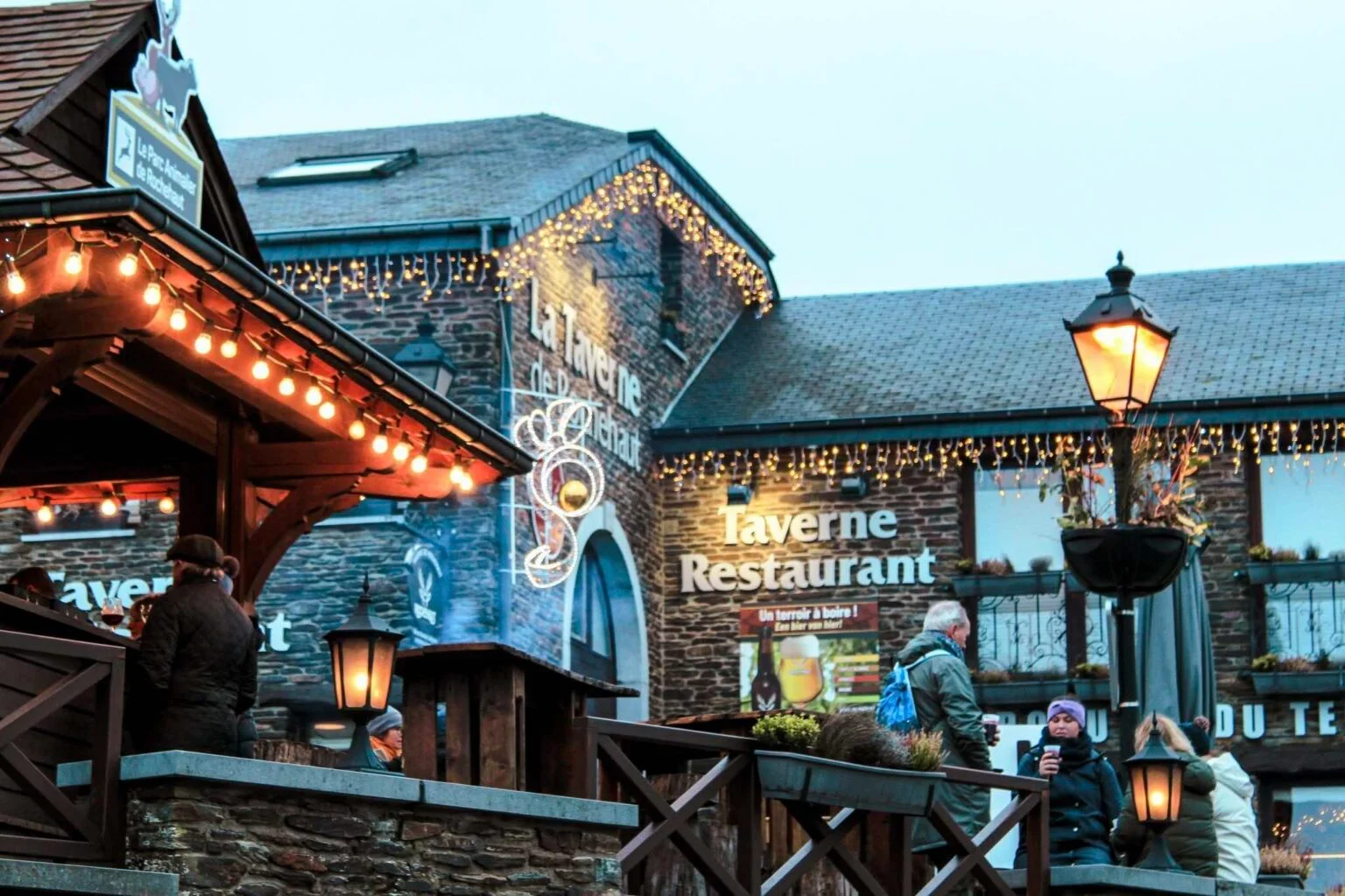 Façade illuminée de la Taverne de Rochehaut en soirée